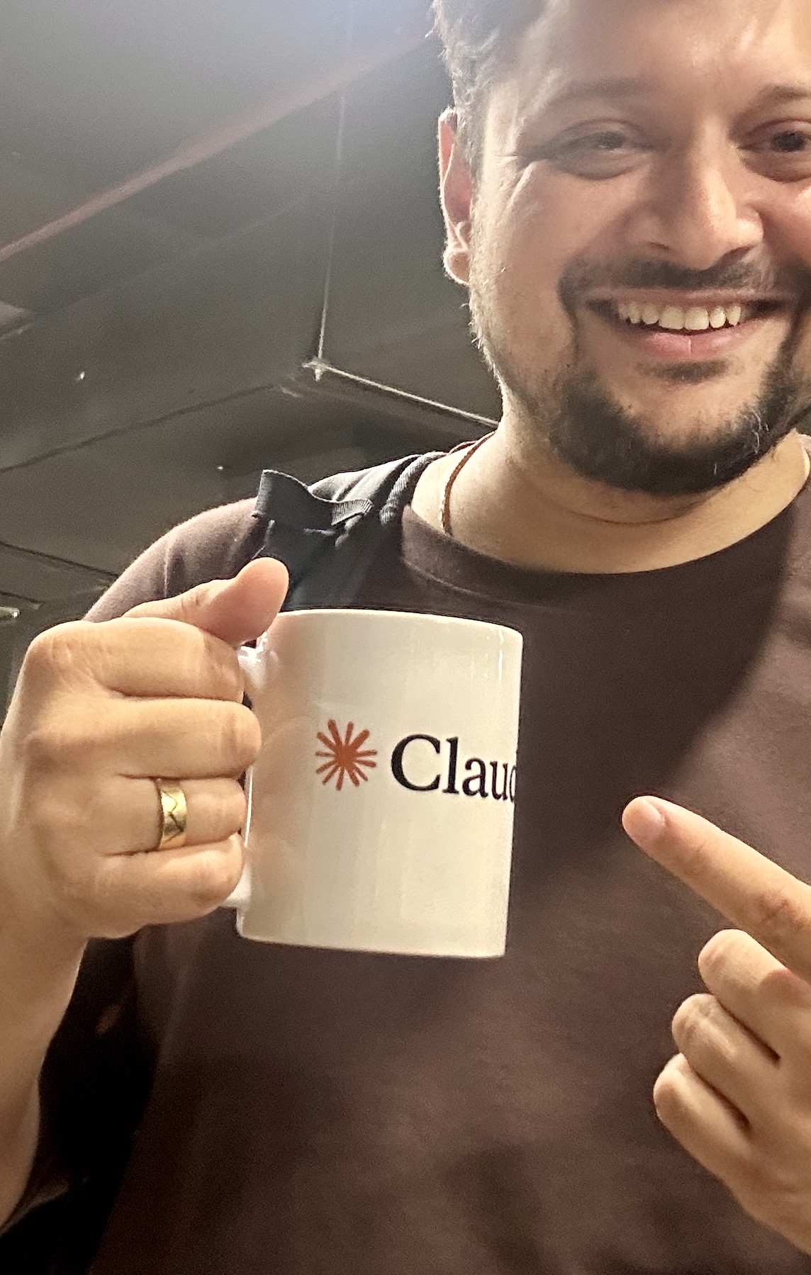 Harshal Saraf holding a Claude-branded mug at the meetup